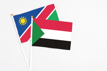Sudan and Namibia stick flags on white background. High quality fabric, miniature national flag. Peaceful global concept.White floor for copy space.