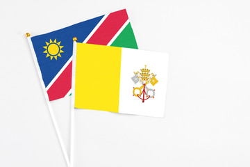 Vatican City and Namibia stick flags on white background. High quality fabric, miniature national flag. Peaceful global concept.White floor for copy space.