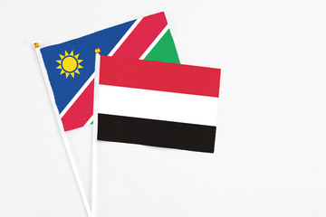 Yemen and Namibia stick flags on white background. High quality fabric, miniature national flag. Peaceful global concept.White floor for copy space.