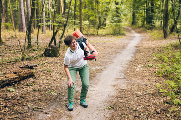 Young woman having trouble feeling knee pain during travel in forest. Injury on way to camp. female tourist got leg injury in forest and gets hurt. Health problem in journey. Theme Insurance Company