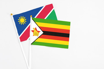 Zimbabwe and Namibia stick flags on white background. High quality fabric, miniature national flag. Peaceful global concept.White floor for copy space.