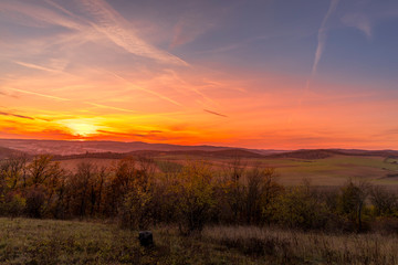 Sunset overlooking nature and landscape from Brno hill sunset couple of moments before sunset orange color with clouds moving in the background and planes flying in the sky.