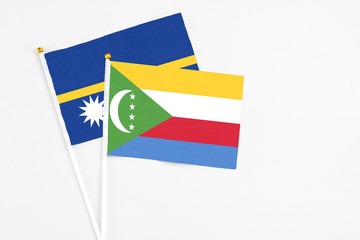Comoros and Nauru stick flags on white background. High quality fabric, miniature national flag. Peaceful global concept.White floor for copy space.