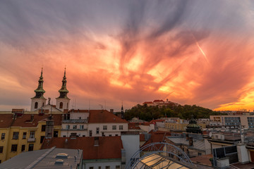 Fototapeta premium Castle Spilberk Brno Europe, Czech city, moving colored orange and blue clouds and sky with view on the area around the castle and church day to night capture.