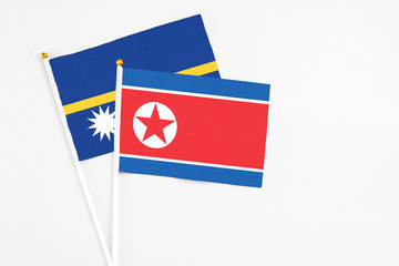 North Korea and Nauru stick flags on white background. High quality fabric, miniature national flag. Peaceful global concept.White floor for copy space.