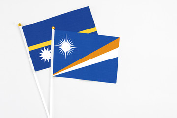 Marshall Islands and Nauru stick flags on white background. High quality fabric, miniature national flag. Peaceful global concept.White floor for copy space.