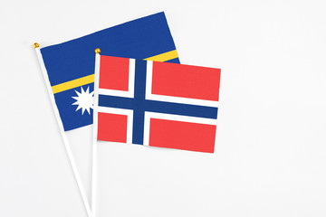 Norway and Nauru stick flags on white background. High quality fabric, miniature national flag. Peaceful global concept.White floor for copy space.