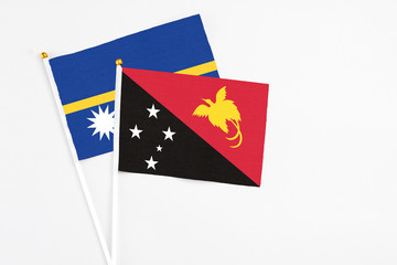 Papua New Guinea and Nauru stick flags on white background. High quality fabric, miniature national flag. Peaceful global concept.White floor for copy space.
