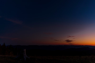 Colorful time-lapse sunset with old abandoned tree trunk and main subject colorful sky with orange and blue colors sunset captured in high mountains Beskydy area Czech Republic.