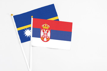 Serbia and Nauru stick flags on white background. High quality fabric, miniature national flag. Peaceful global concept.White floor for copy space.