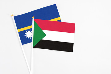Sudan and Nauru stick flags on white background. High quality fabric, miniature national flag. Peaceful global concept.White floor for copy space.