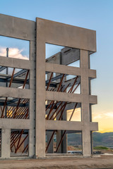 Exterior of modern building under construction against sky and clouds at sunset