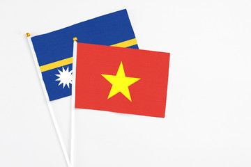 Vietnam and Nauru stick flags on white background. High quality fabric, miniature national flag. Peaceful global concept.White floor for copy space.