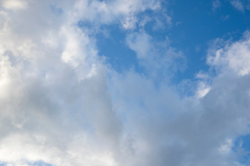 Fast moving clouds during a sunny day in the blue sky with the transition to evening hours along with the occasional flight of the aircraft leaving white traces on a flyby.
