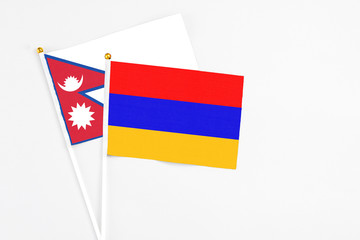 Armenia and Nepal stick flags on white background. High quality fabric, miniature national flag. Peaceful global concept.White floor for copy space.