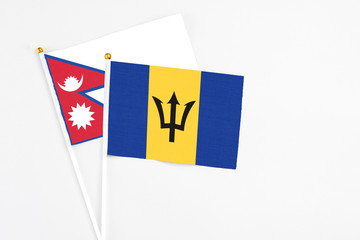 Barbados and Nepal stick flags on white background. High quality fabric, miniature national flag. Peaceful global concept.White floor for copy space.
