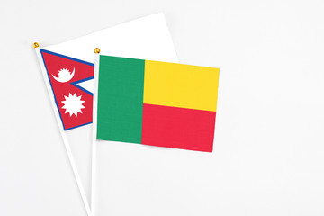 Benin and Nepal stick flags on white background. High quality fabric, miniature national flag. Peaceful global concept.White floor for copy space.