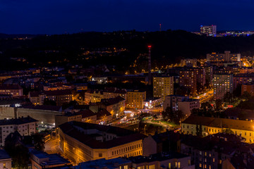 Fototapeta premium Crossing during late day to night timelapse to Mendel Square in Brno with cars and public transport, trams and buses passing through busy square and the surrounding streets which slowly light up.