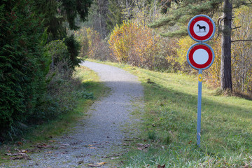 Naklejka premium forest road in the day with driving prohibition and horses prohibition sign