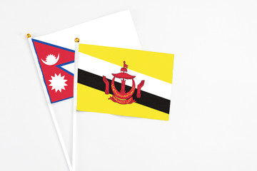 Brunei and Nepal stick flags on white background. High quality fabric, miniature national flag. Peaceful global concept.White floor for copy space.