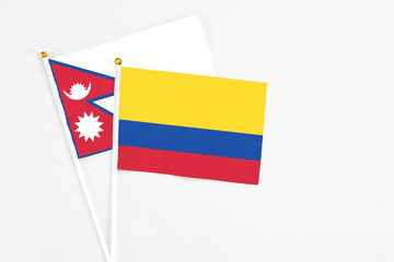 Colombia and Nepal stick flags on white background. High quality fabric, miniature national flag. Peaceful global concept.White floor for copy space.