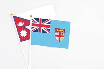 Fototapeta premium Fiji and Nepal stick flags on white background. High quality fabric, miniature national flag. Peaceful global concept.White floor for copy space.