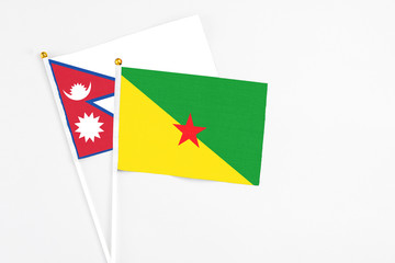 French Guiana and Nepal stick flags on white background. High quality fabric, miniature national flag. Peaceful global concept.White floor for copy space.