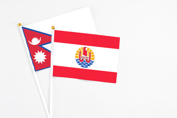 French Polynesia and Nepal stick flags on white background. High quality fabric, miniature national flag. Peaceful global concept.White floor for copy space.