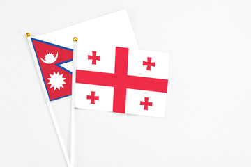 Georgia and Nepal stick flags on white background. High quality fabric, miniature national flag. Peaceful global concept.White floor for copy space.