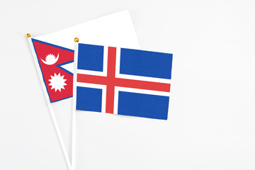 Obraz premium Iceland and Nepal stick flags on white background. High quality fabric, miniature national flag. Peaceful global concept.White floor for copy space.