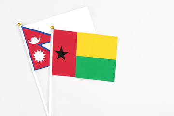Guinea Bissau and Nepal stick flags on white background. High quality fabric, miniature national flag. Peaceful global concept.White floor for copy space.