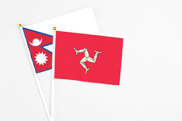 Isle Of Man and Nepal stick flags on white background. High quality fabric, miniature national flag. Peaceful global concept.White floor for copy space.
