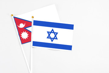 Israel and Nepal stick flags on white background. High quality fabric, miniature national flag. Peaceful global concept.White floor for copy space.