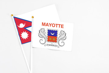 Mayotte and Nepal stick flags on white background. High quality fabric, miniature national flag. Peaceful global concept.White floor for copy space.