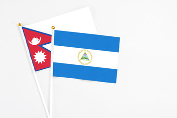Nicaragua and Nepal stick flags on white background. High quality fabric, miniature national flag. Peaceful global concept.White floor for copy space.