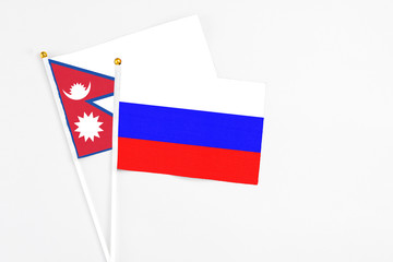 Russia and Nepal stick flags on white background. High quality fabric, miniature national flag. Peaceful global concept.White floor for copy space.
