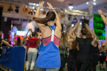 Fototapeta na wymiar Fitness Workout in Gym: People doing Exercises in Class with Music and Teacher on Stage