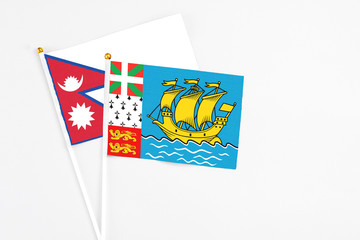 Saint Pierre And Miquelon and Nepal stick flags on white background. High quality fabric, miniature national flag. Peaceful global concept.White floor for copy space.