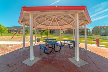 Octagon shape pavilion with blue tables and benches at a neighborhood park