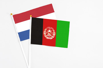 Afghanistan and Netherlands stick flags on white background. High quality fabric, miniature national flag. Peaceful global concept.White floor for copy space.