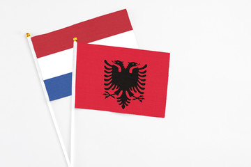 Albania and Netherlands stick flags on white background. High quality fabric, miniature national flag. Peaceful global concept.White floor for copy space.