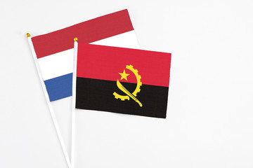 Angola and Netherlands stick flags on white background. High quality fabric, miniature national flag. Peaceful global concept.White floor for copy space.