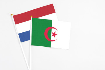 Algeria and Netherlands stick flags on white background. High quality fabric, miniature national flag. Peaceful global concept.White floor for copy space.