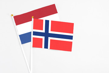 Obraz premium Bouvet Islands and Netherlands stick flags on white background. High quality fabric, miniature national flag. Peaceful global concept.White floor for copy space.