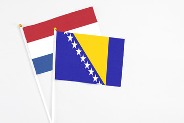 Bosnia Herzegovina and Netherlands stick flags on white background. High quality fabric, miniature national flag. Peaceful global concept.White floor for copy space.