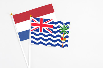 Fototapeta premium British Indian Ocean Territory and Netherlands stick flags on white background. High quality fabric, miniature national flag. Peaceful global concept.White floor for copy space.