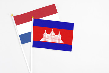 Cambodia and Netherlands stick flags on white background. High quality fabric, miniature national flag. Peaceful global concept.White floor for copy space.