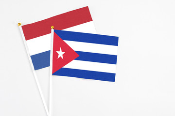 Cuba and Netherlands stick flags on white background. High quality fabric, miniature national flag. Peaceful global concept.White floor for copy space.