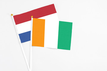 Fototapeta premium Cote D'Ivoire and Netherlands stick flags on white background. High quality fabric, miniature national flag. Peaceful global concept.White floor for copy space.