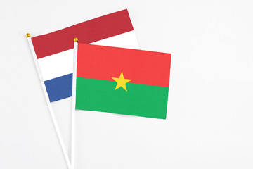 Burkina Faso and Netherlands stick flags on white background. High quality fabric, miniature national flag. Peaceful global concept.White floor for copy space.
